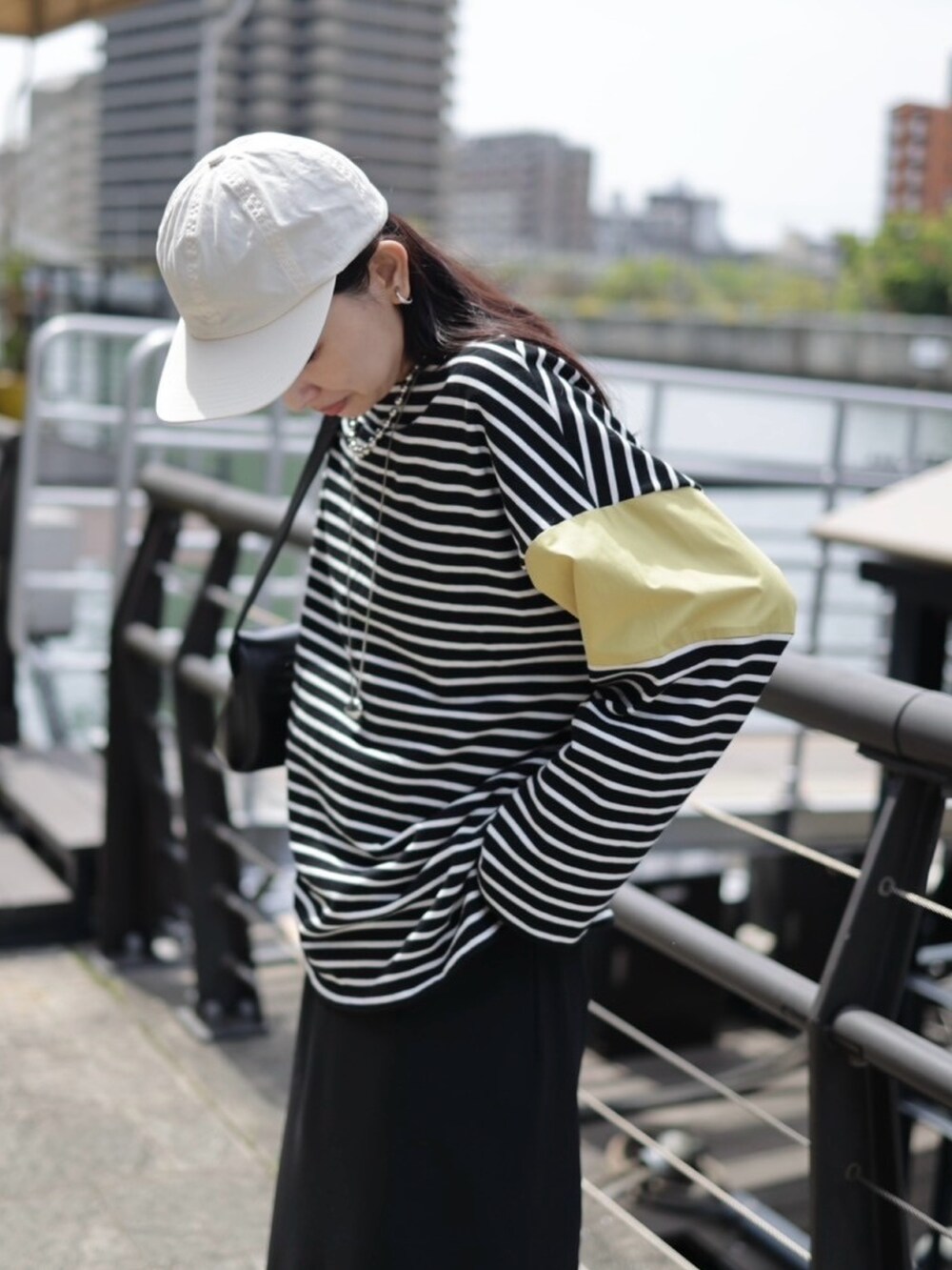 イエロー系のTシャツ/カットソー、ホワイト系のスニーカー、ブラック系のショルダーバッグを着用したレディースの春コーディネートの2枚目の写真