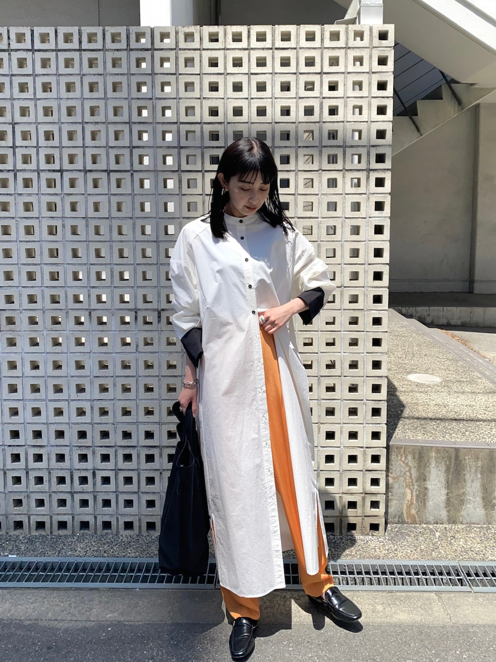 ブラック系のシャツワンピース、ブラック系のトートバッグ、オレンジ系のその他パンツを着用したレディースの春コーディネートの3枚目の写真