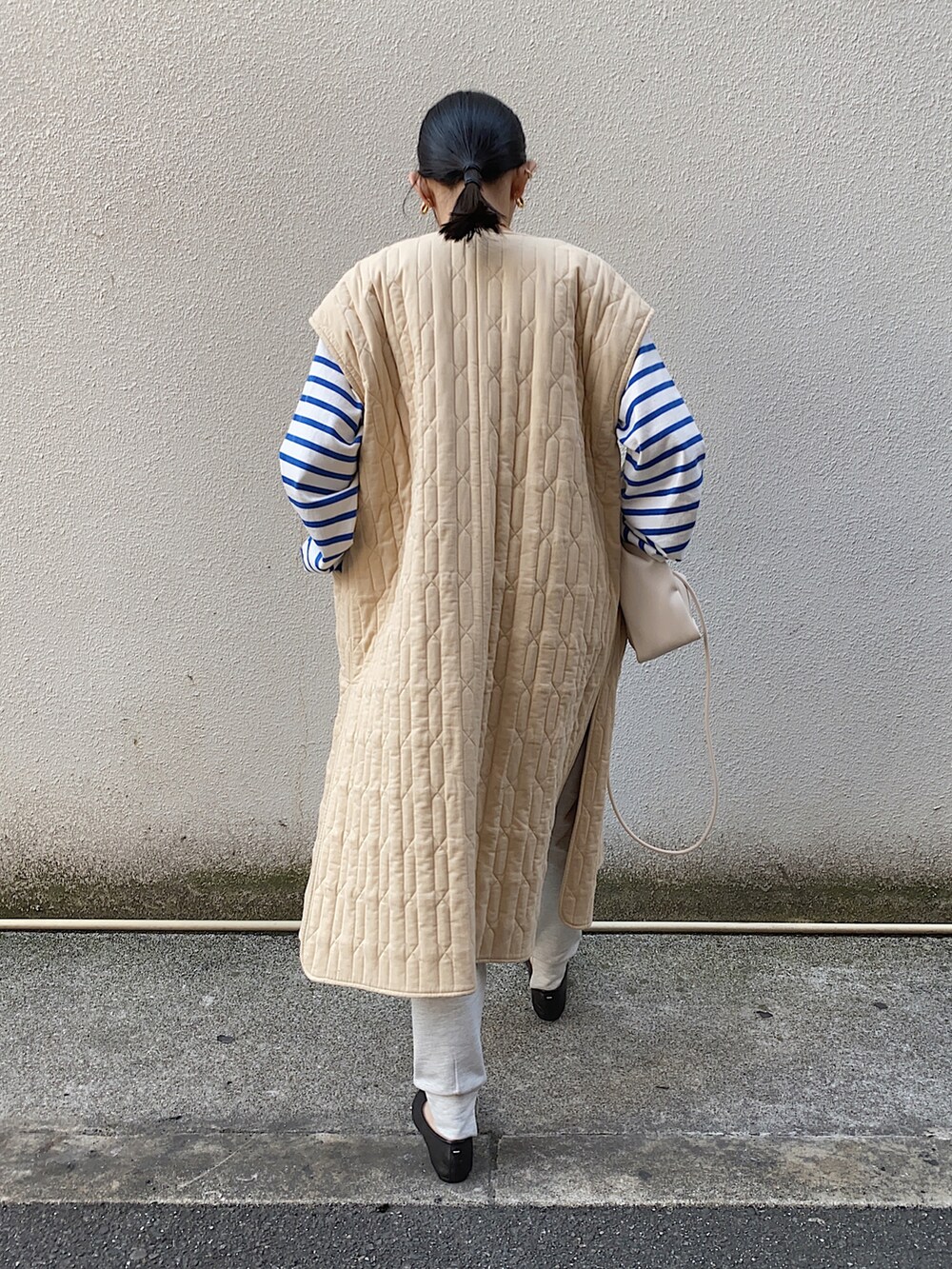 ベージュ系のミリタリージャケット、グレー系のスウェットパンツ、ホワイト系のハンドバッグを着用したレディースの春コーディネートの2枚目の写真