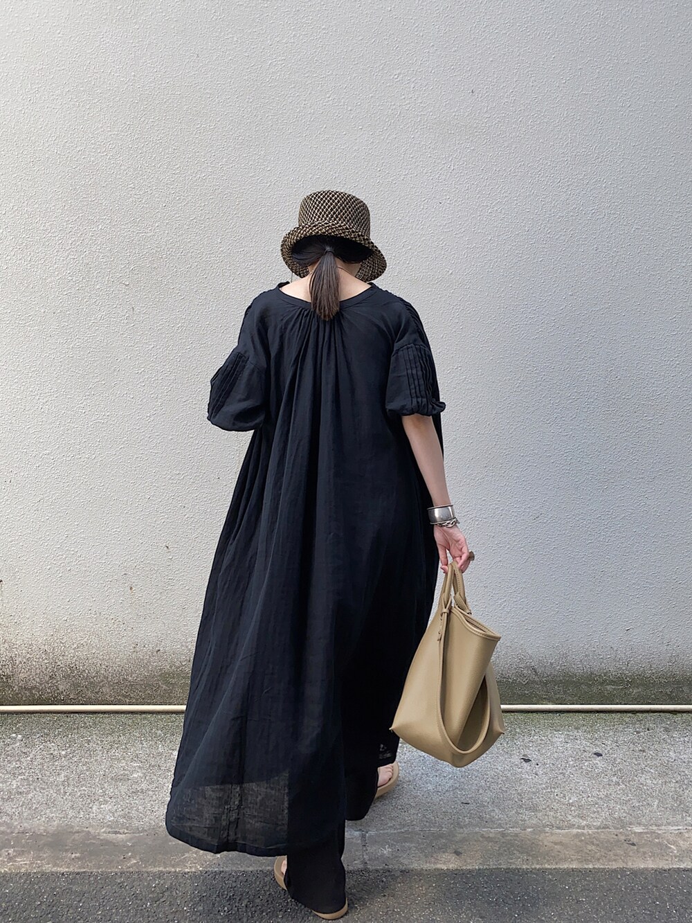 ブラック系のワンピース、ベージュ系のハンドバッグ、ベージュ系のサンダルを着用したレディースの夏コーディネートの2枚目の写真