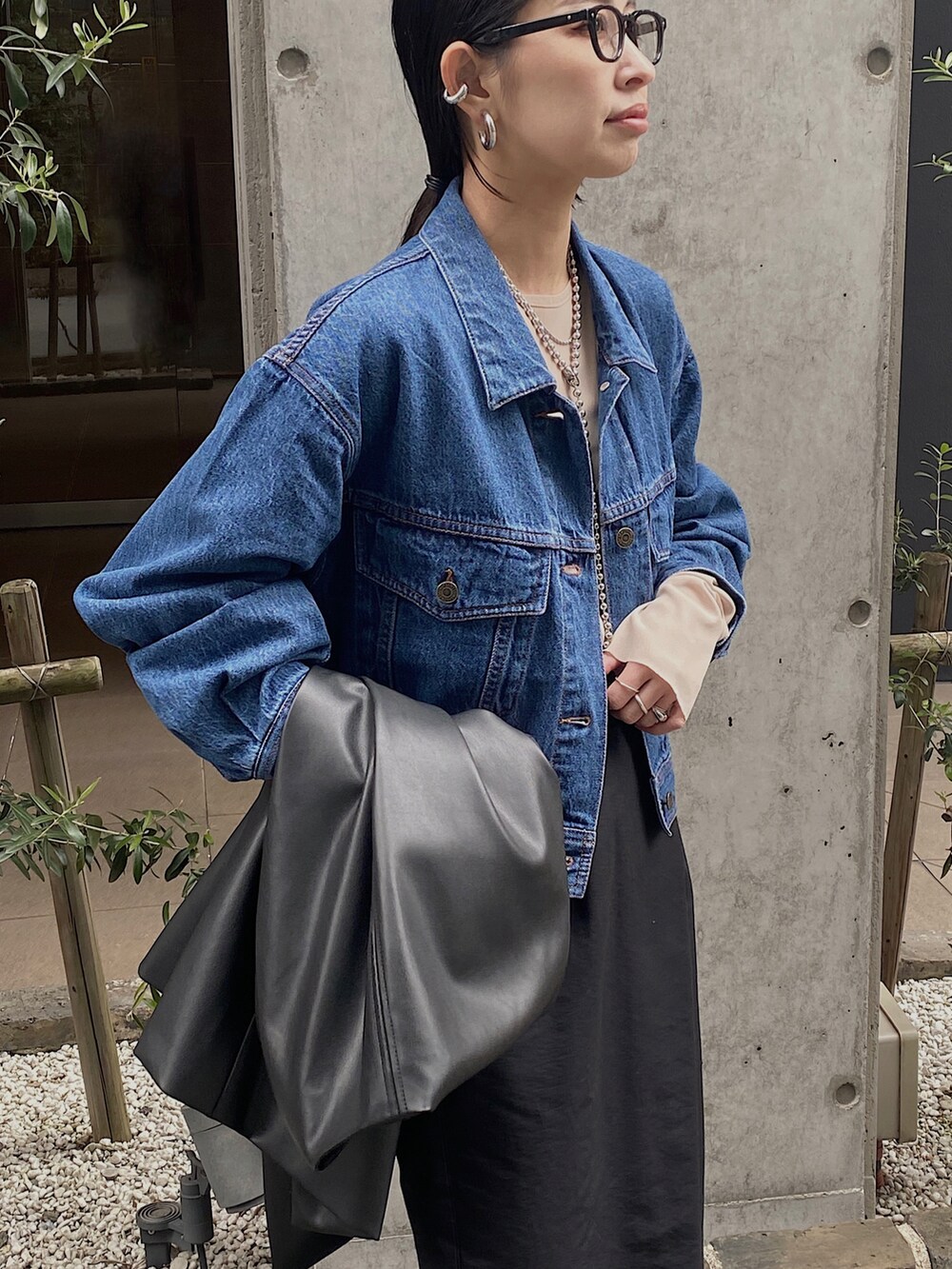 ブルー系のデニムジャケット、ブラック系のベスト、ベージュ系のTシャツ/カットソーを着用したレディースの冬コーディネートの4枚目の写真