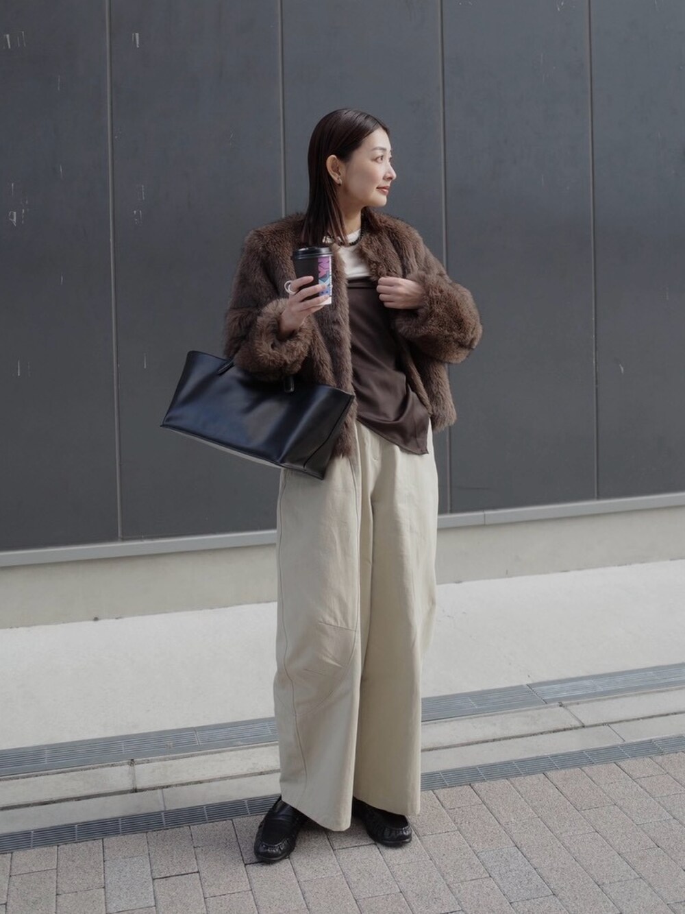 ベージュ系のチノパンツ、ブラウン系のノーカラージャケット、ブラック系のトートバッグを着用したレディースの秋コーディネートの2枚目の写真