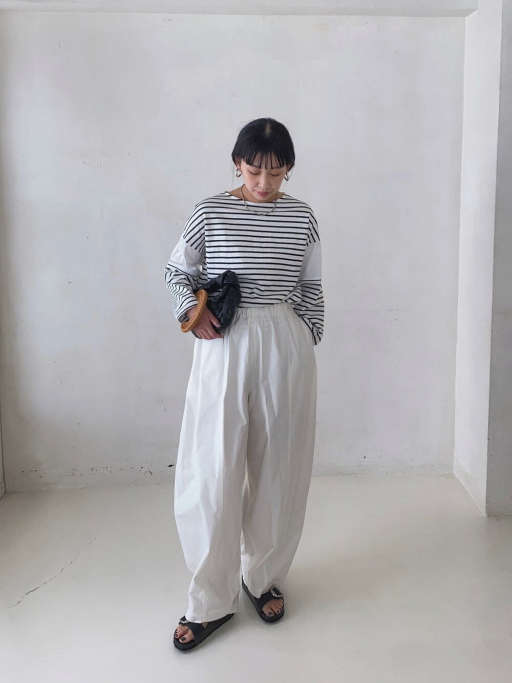 ホワイト系のTシャツ/カットソー、ホワイト系のチノパンツ、ブラック系のサンダルを着用したレディースの春コーディネートの2枚目の写真