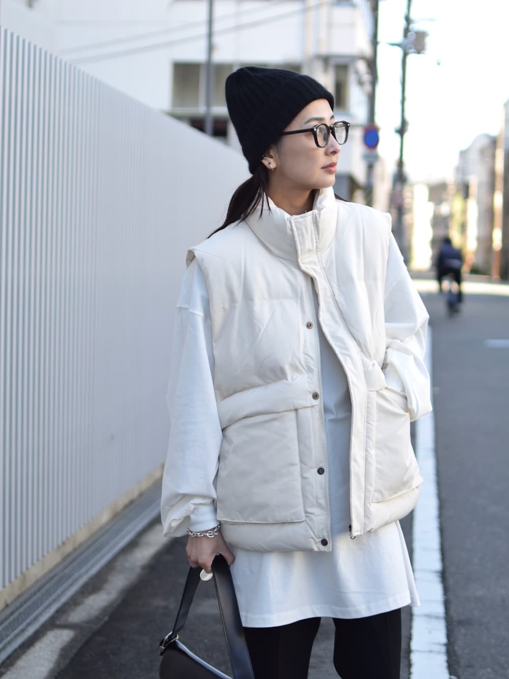 ホワイト系のダウンベスト、ブラック系のその他パンツ、ブラック系のショルダーバッグを着用したレディースの冬コーディネートの3枚目の写真