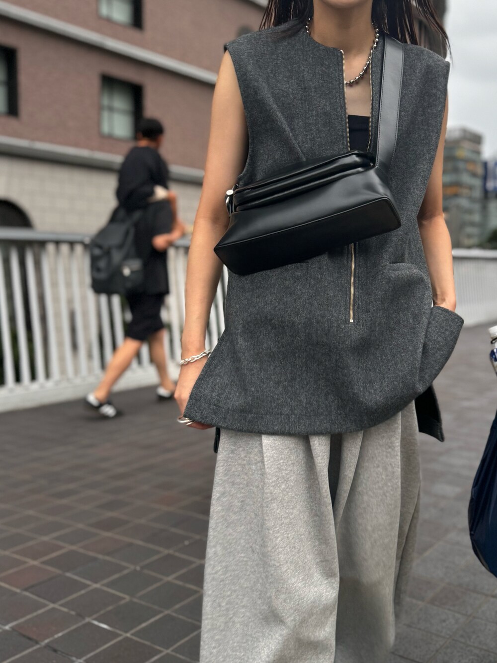 グレー系のベスト、グレー系のスウェットパンツ、シルバー系のサンダルを着用したレディースの秋コーディネートの3枚目の写真