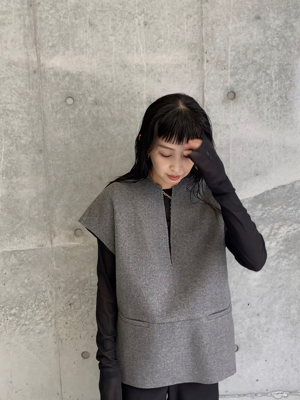 グレー系のベスト、ブラック系のその他パンツ、ゴールド系のネックレスを着用したレディースの秋コーディネートの2枚目の写真