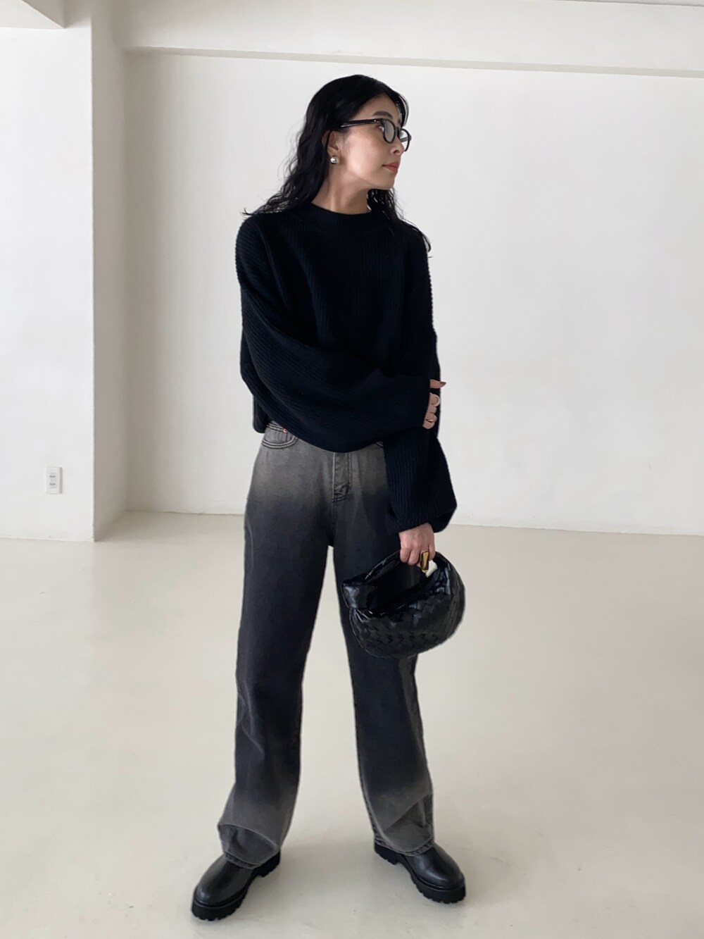 ブラック系のニット/セーター、ブラック系のデニムパンツ、ブラック系のブーツを着用したレディースの春コーディネートの3枚目の写真