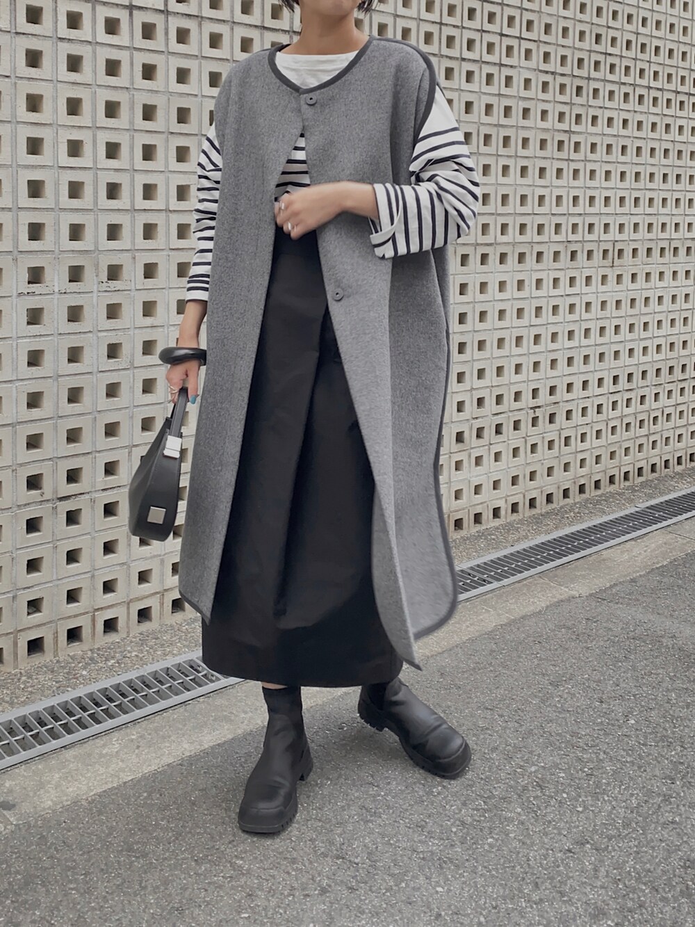 グレー系のその他アウター、ホワイト系のTシャツ/カットソー、ブラック系のハンドバッグを着用したレディースの秋コーディネートの3枚目の写真