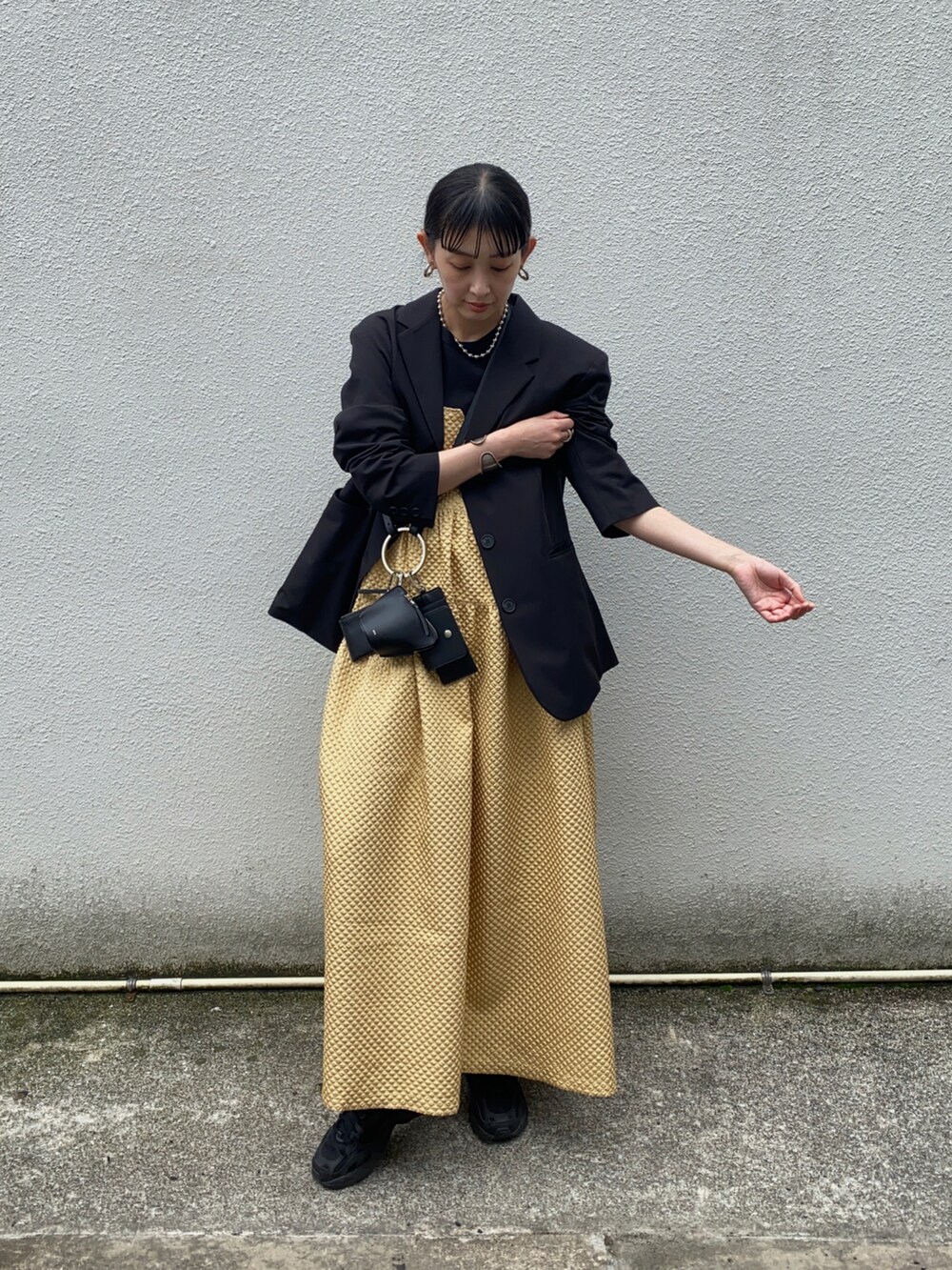 ブラック系のテーラードジャケット、ブラック系のショルダーバッグ、ブラック系のスニーカーを着用したレディースの春コーディネートの3枚目の写真