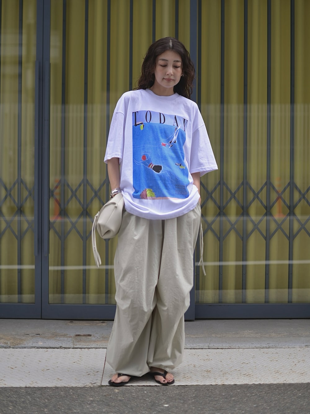ホワイト系のTシャツ/カットソー、ホワイト系のショルダーバッグ、グレー系のパンツを着用したレディースの夏コーディネートの2枚目の写真
