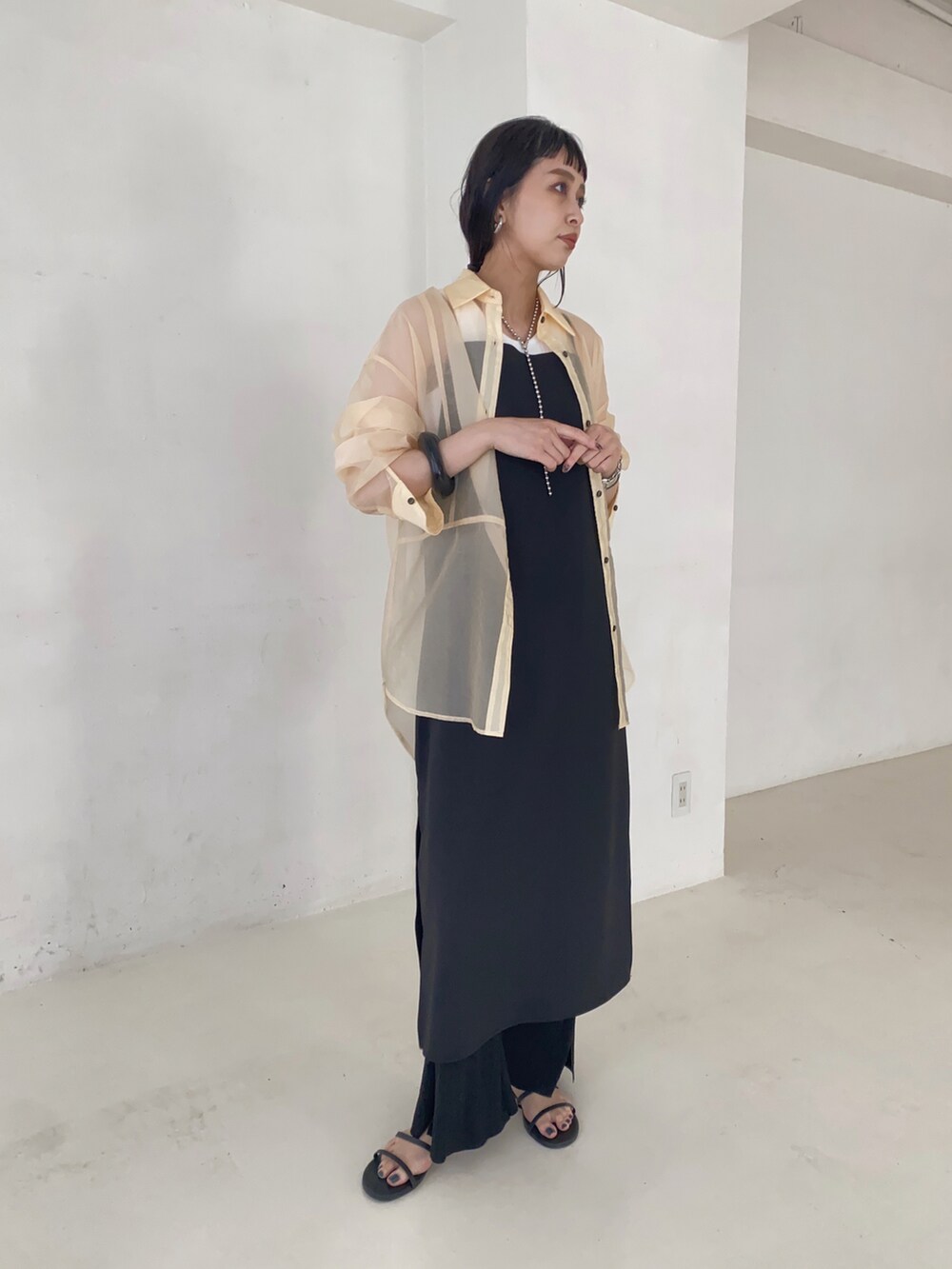 ブラック系のワンピース、ホワイト系のシャツ/ブラウス、ブラック系のサンダルを着用したレディースの夏コーディネートの2枚目の写真