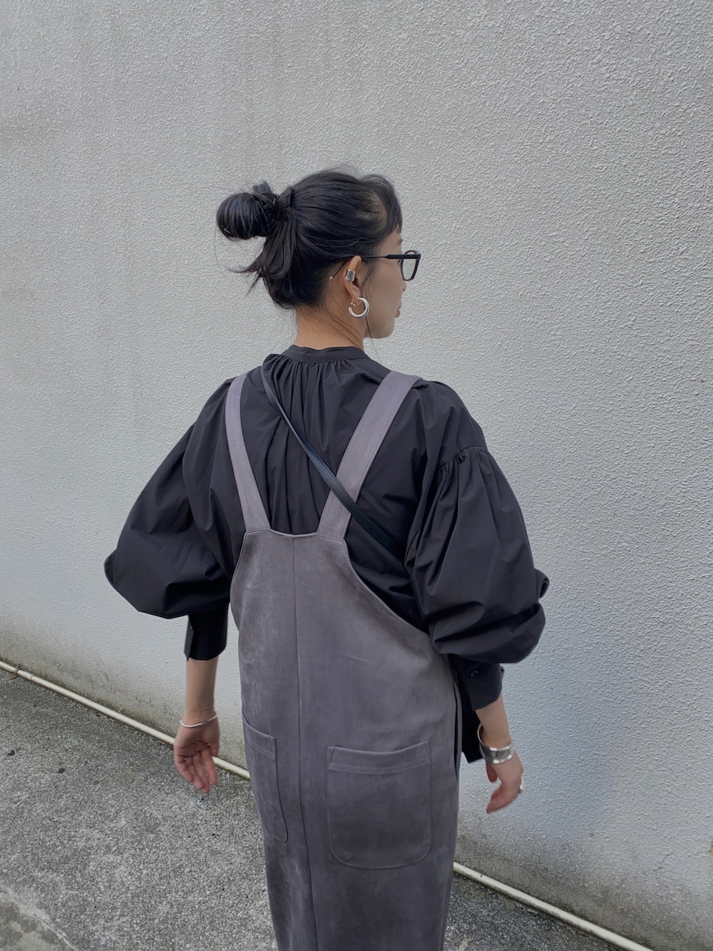 グレー系のジャンパースカート、ブラック系のシャツ/ブラウス、ブラック系のブーツを着用したレディースの冬コーディネートの3枚目の写真