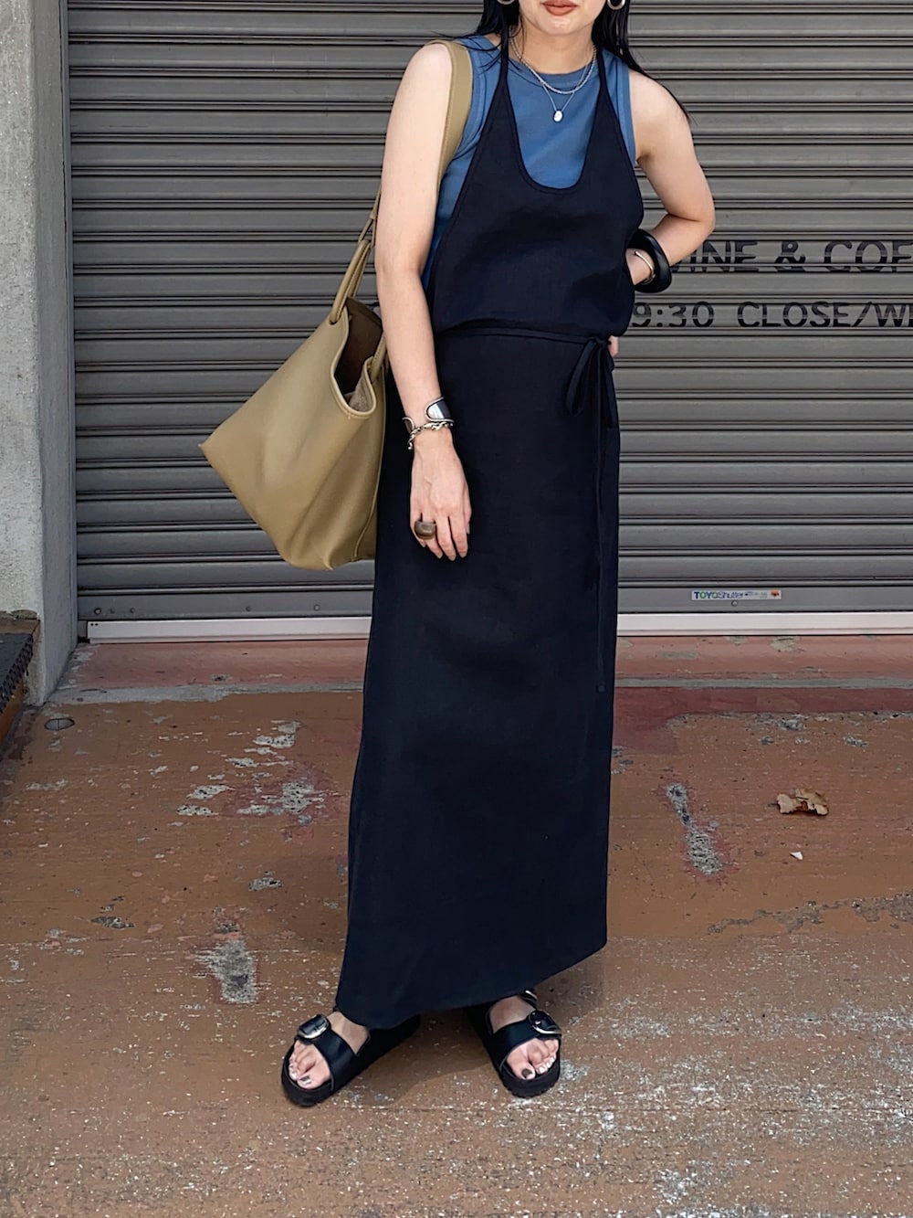 ブラック系のワンピース、ベージュ系のハンドバッグ、ブルー系のタンクトップを着用したレディースの夏コーディネートの2枚目の写真