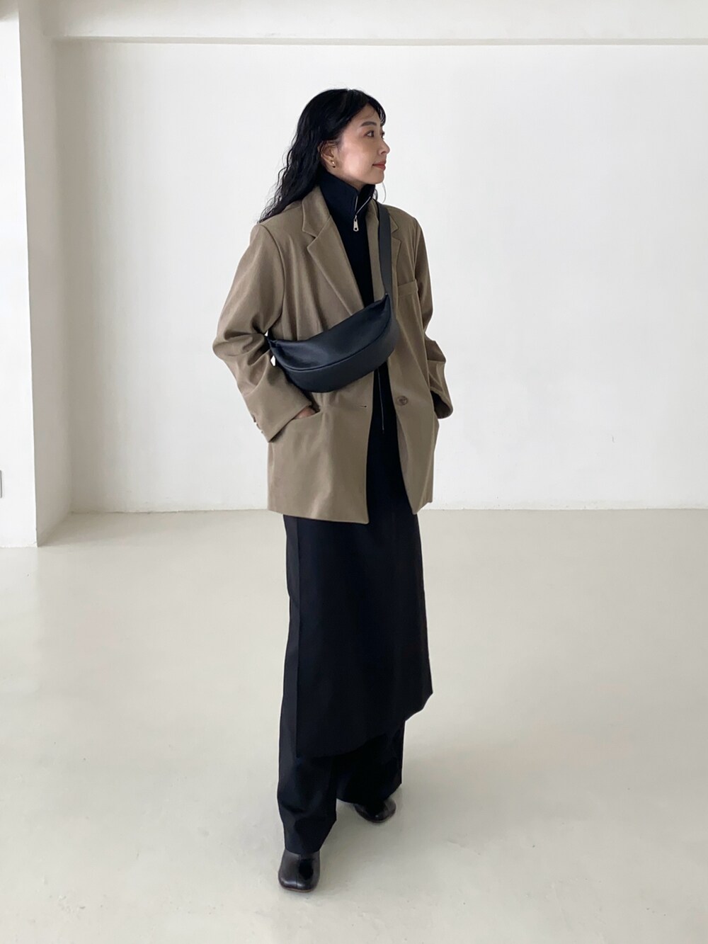 ベージュ系のテーラードジャケット、ブラック系のベスト、ブラック系のショルダーバッグを着用したレディースの冬コーディネートの4枚目の写真