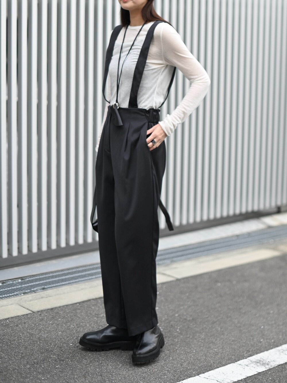 グレー系のスラックス、ブラック系のブーツ、ブラック系のショルダーバッグを着用したレディースの冬コーディネートの3枚目の写真