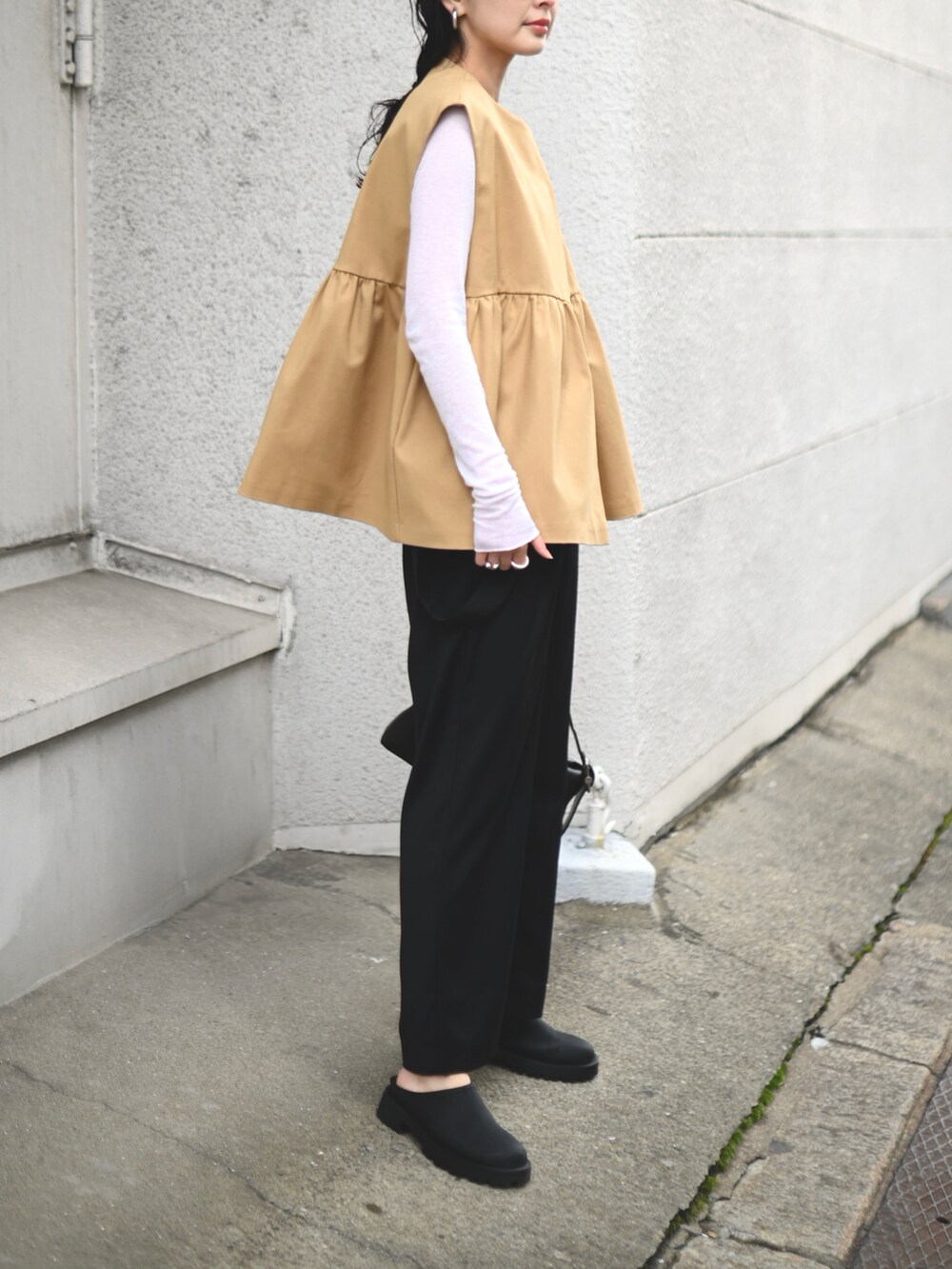 ベージュ系のベスト、ブラック系のショルダーバッグ、ブラック系のスラックスを着用したレディースの春コーディネートの3枚目の写真