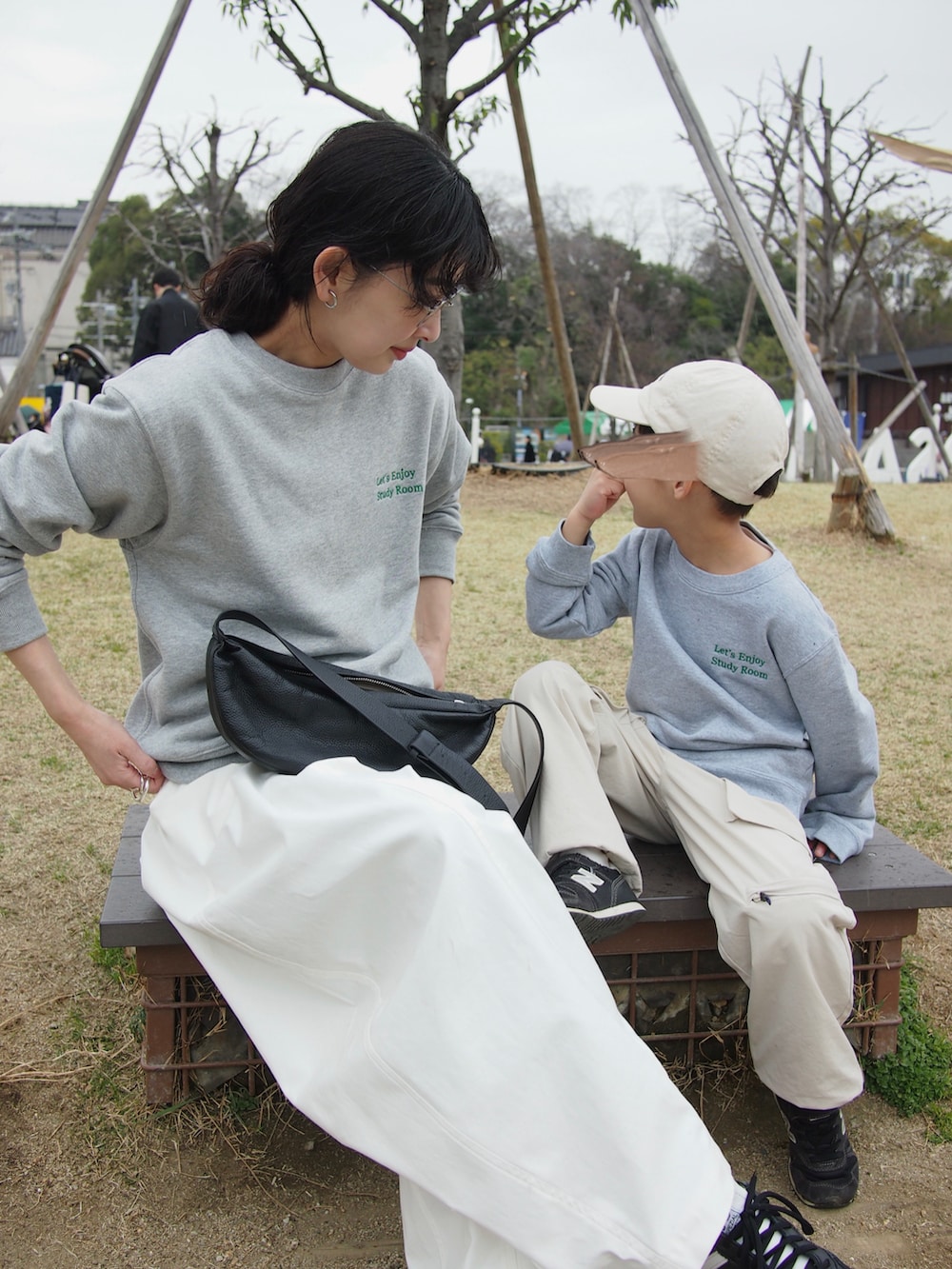 グレー系のスウェット、ブラック系のスニーカー、ホワイト系のチノパンツを着用したレディースの春コーディネートの2枚目の写真