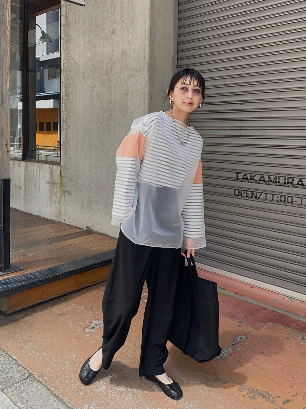 オレンジ系のTシャツ/カットソー、ブラック系のその他パンツ、ブラック系のバレエシューズを着用したレディースの春コーディネートの4枚目の写真