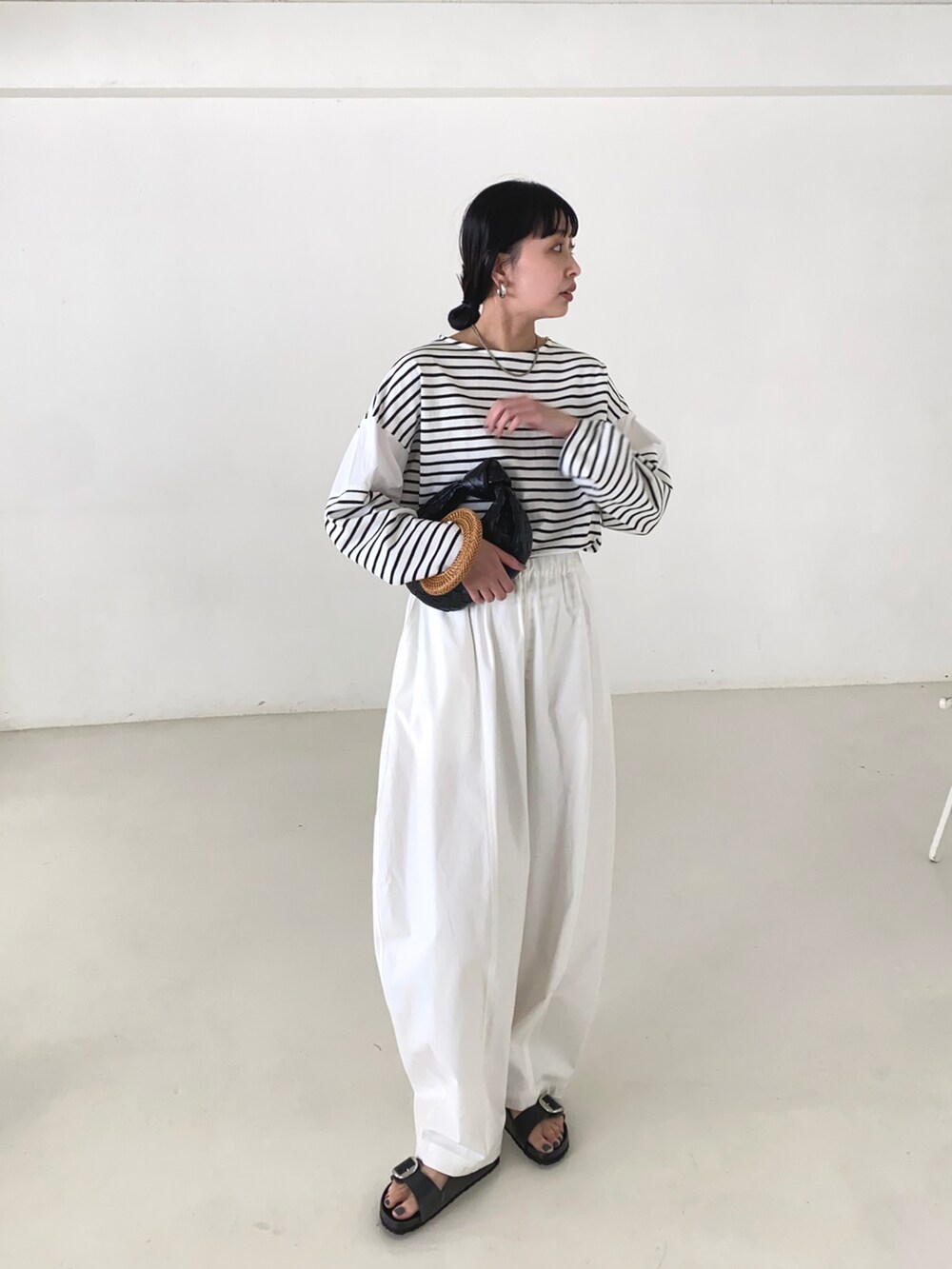 ホワイト系のTシャツ/カットソー、ホワイト系のチノパンツ、ブラック系のサンダルを着用したレディースの春コーディネートの4枚目の写真