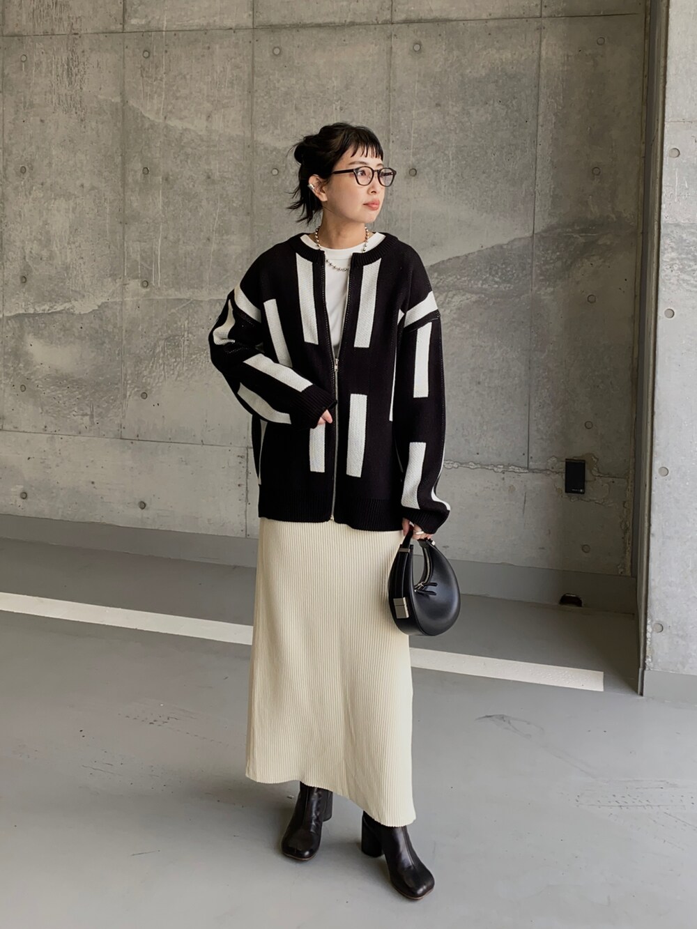 ブラック系のカーディガン/ボレロ、ホワイト系のスカート、ブラック系のハンドバッグを着用したレディースの冬コーディネートの3枚目の写真