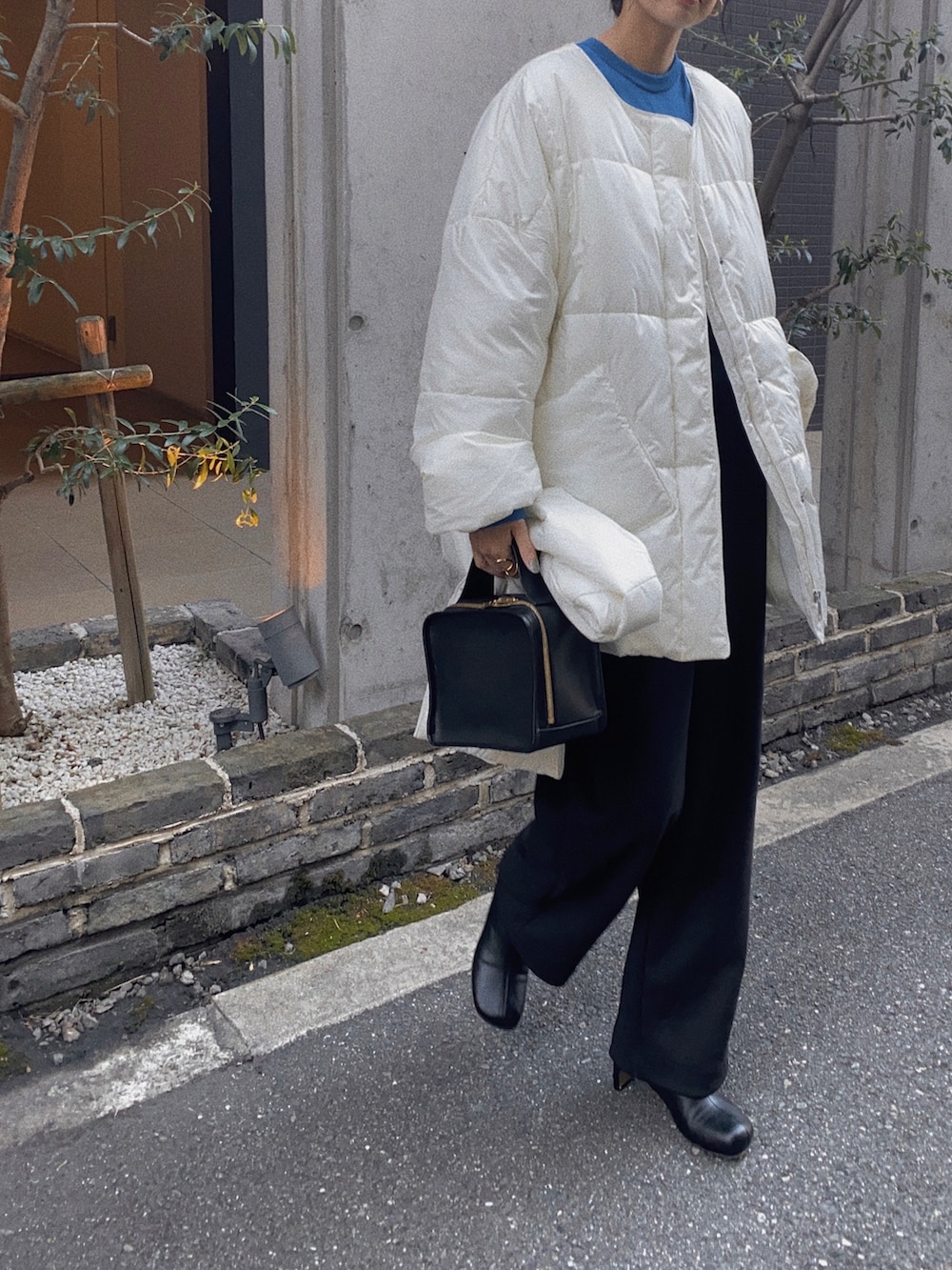 ホワイト系のダウンジャケット/コート、ブルー系のニット/セーター、ブラック系のサロペット/オーバーオールを着用したレディースの秋コーディネートの2枚目の写真