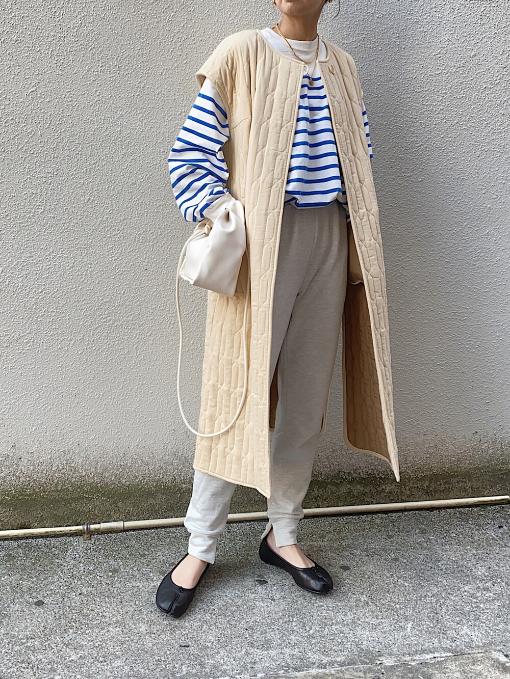 ベージュ系のミリタリージャケット、グレー系のスウェットパンツ、ホワイト系のハンドバッグを着用したレディースの春コーディネートの3枚目の写真