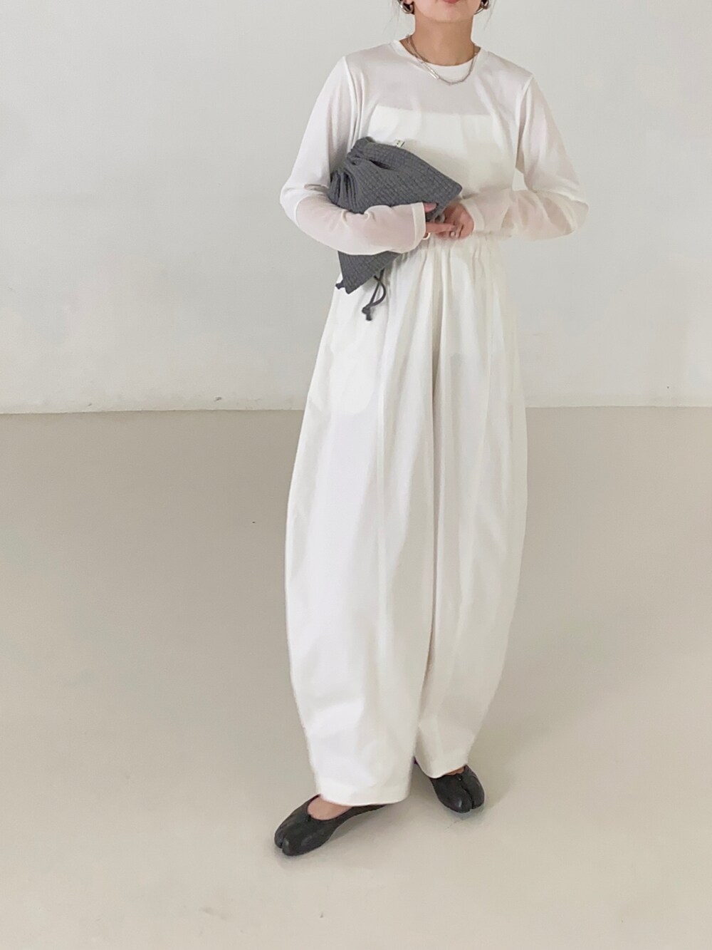 ホワイト系のキャミソール、グレー系のショルダーバッグ、ホワイト系のチノパンツを着用したレディースの夏コーディネートの3枚目の写真