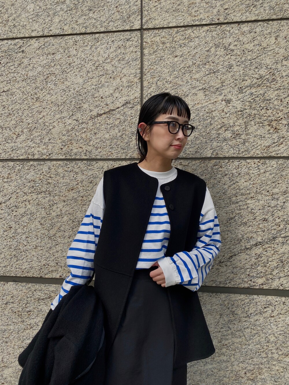 ブルー系のTシャツ/カットソー、ブラック系のチェスターコート、ブラック系のメガネを着用したレディースの冬コーディネートの3枚目の写真