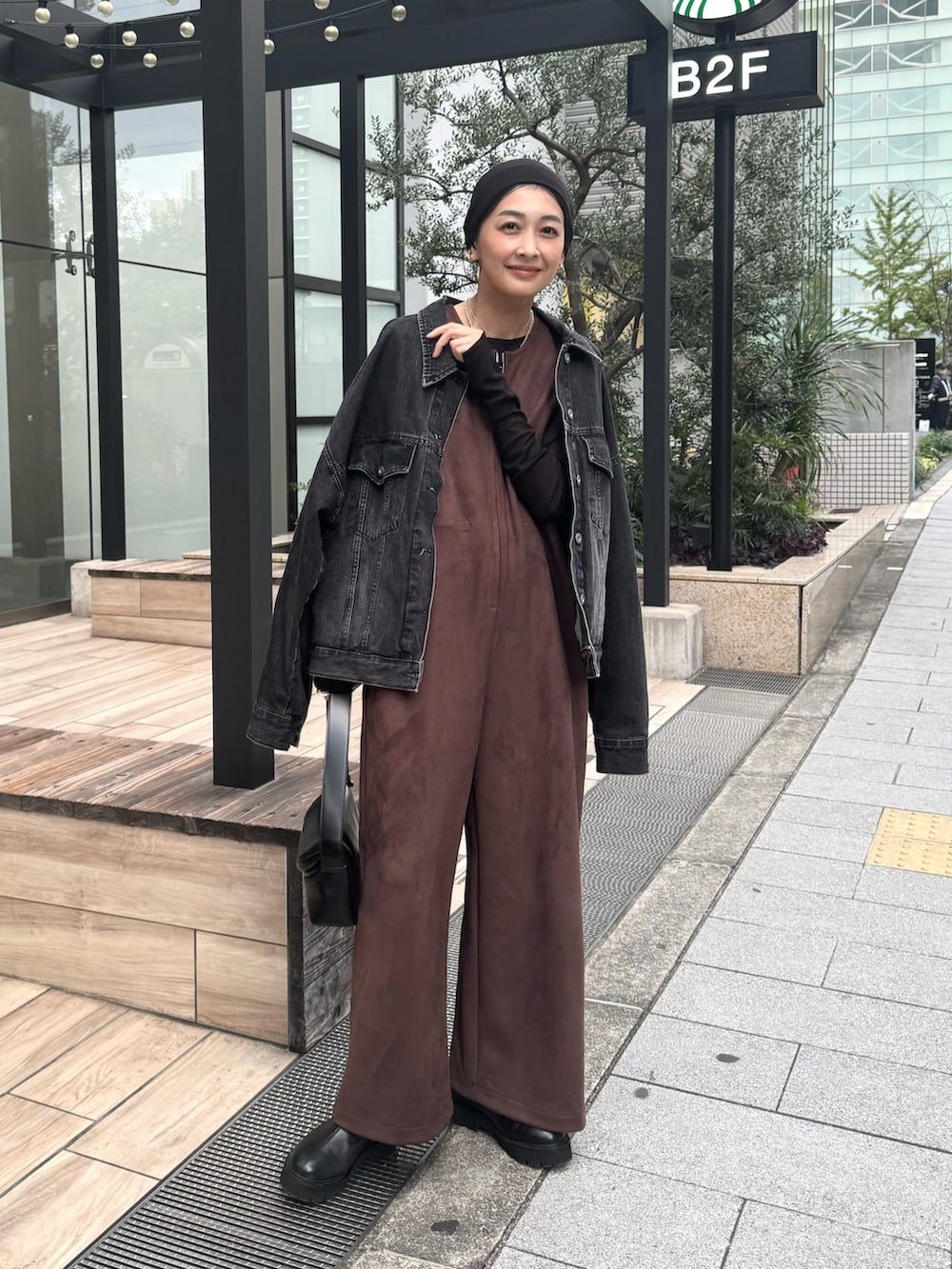 ブラウン系のつなぎ/オールインワン、ブラック系のショルダーバッグ、ブラック系のブーツを着用したレディースの秋コーディネートの5枚目の写真
