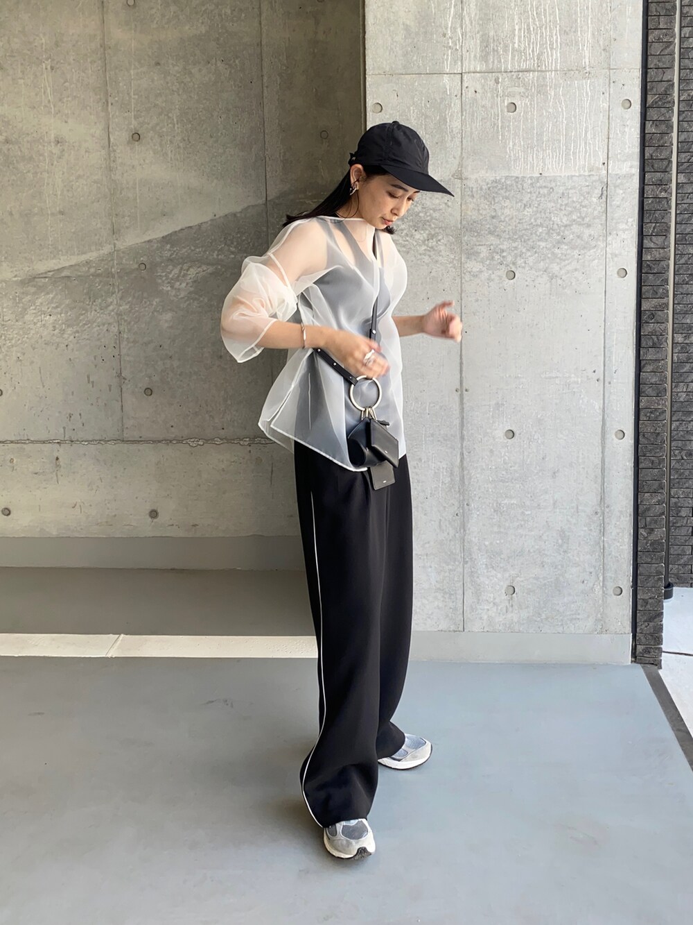 ブラック系のショルダーバッグ、グレー系のスニーカー、ホワイト系のシャツ/ブラウスを着用したレディースの夏コーディネートの3枚目の写真