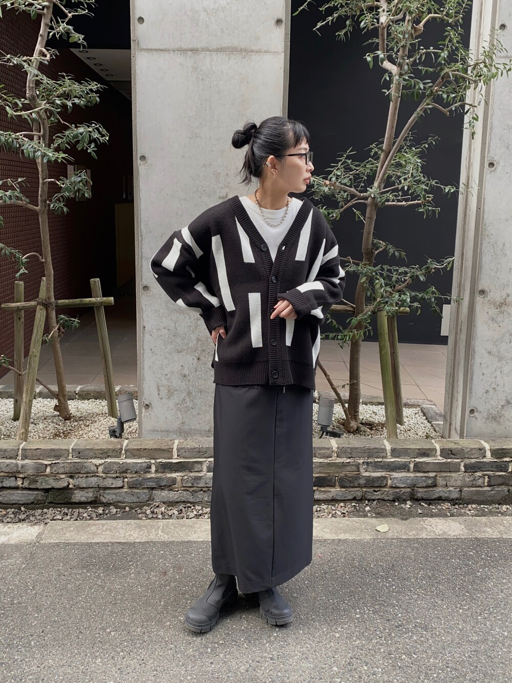 ブラック系のニット/セーター、ブラック系のブーツ、ホワイト系のTシャツ/カットソーを着用したレディースの秋コーディネートの4枚目の写真