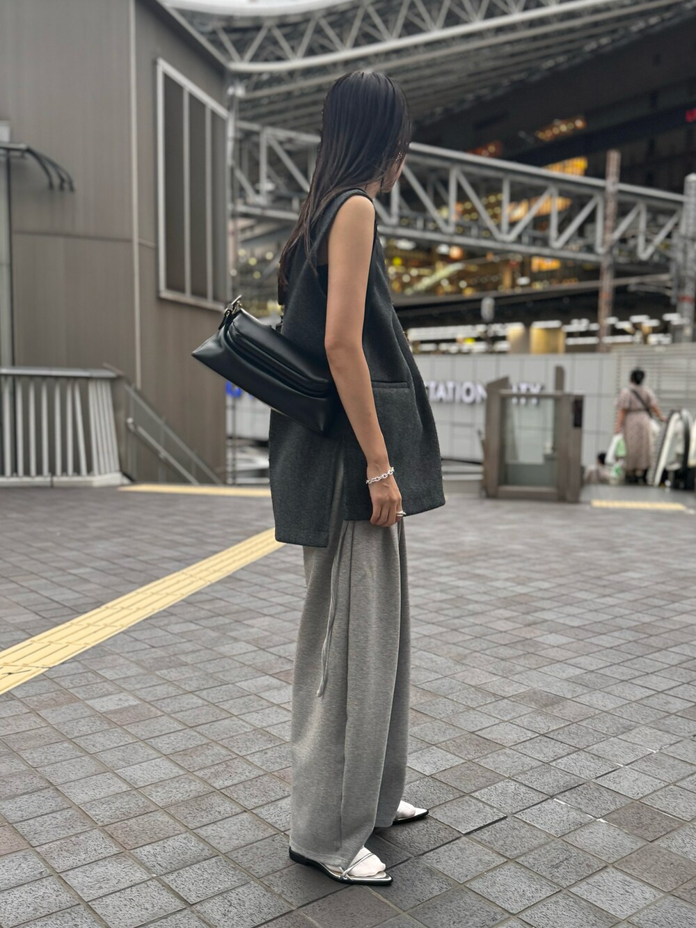 グレー系のベスト、グレー系のスウェットパンツ、シルバー系のサンダルを着用したレディースの秋コーディネートの2枚目の写真
