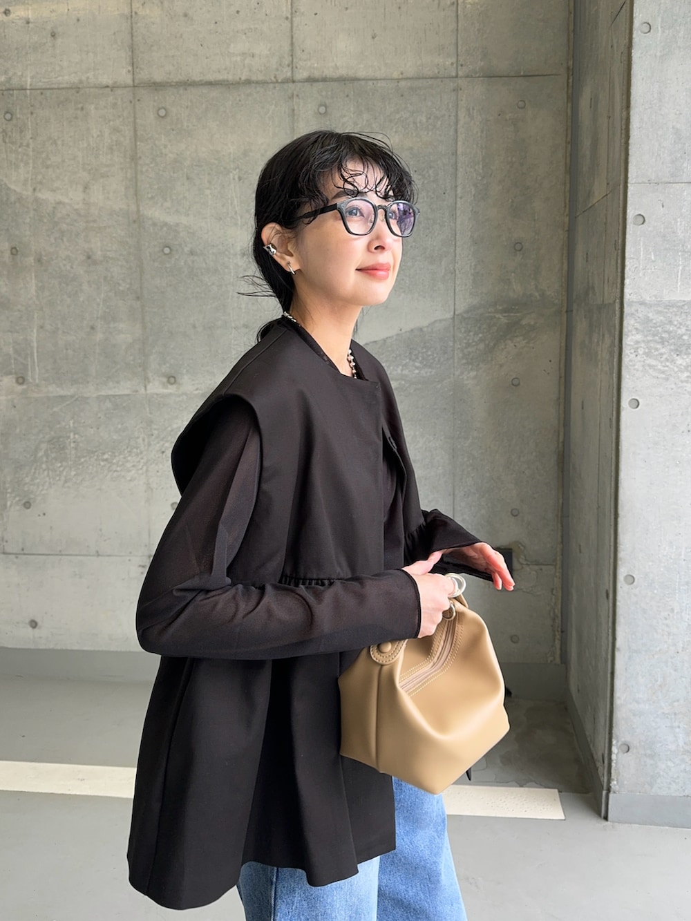 ブラック系のベスト、ブラック系のTシャツ/カットソー、ブルー系のデニムパンツを着用したレディースの春コーディネートの4枚目の写真