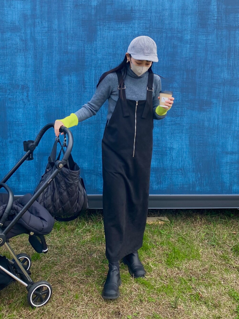 ブラック系のジャンパースカート、グレー系のニット/セーター、グレー系のキャップを着用したレディースの冬コーディネートの2枚目の写真