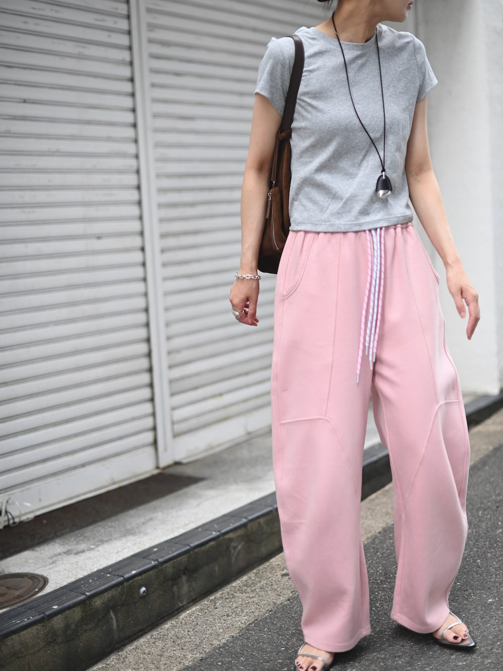 ピンク系のスウェットパンツ、グレー系のTシャツ/カットソー、ブラウン系のトートバッグを着用したレディースの夏コーディネートの3枚目の写真