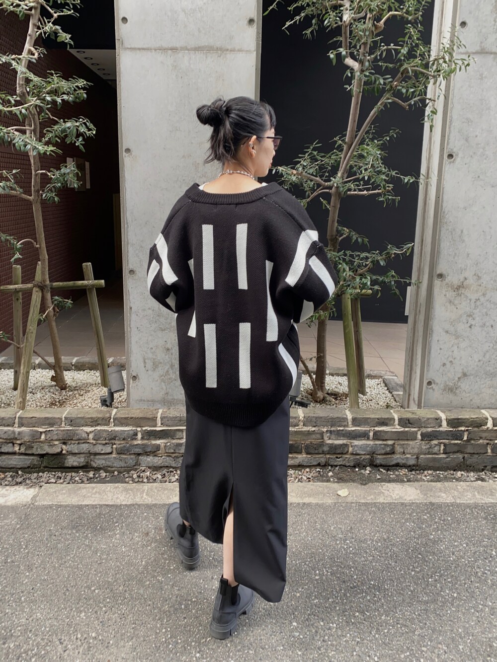 ブラック系のニット/セーター、ブラック系のブーツ、ホワイト系のTシャツ/カットソーを着用したレディースの秋コーディネートの3枚目の写真