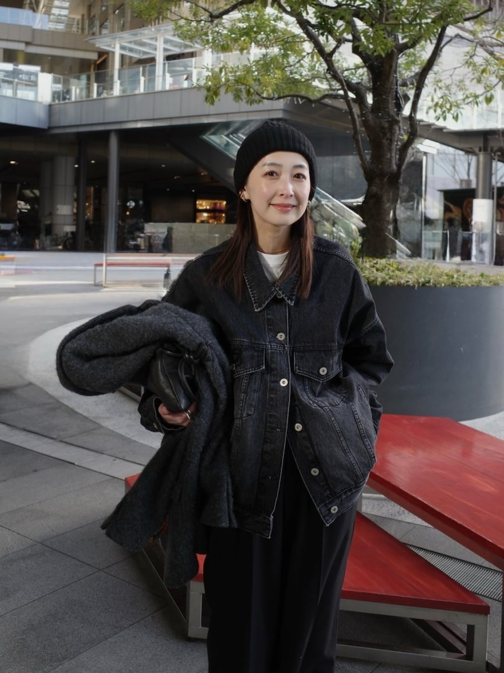 ブラック系のデニムジャケット、ブラック系のスラックス、ブラック系のローファーを着用したレディースの冬コーディネートの2枚目の写真