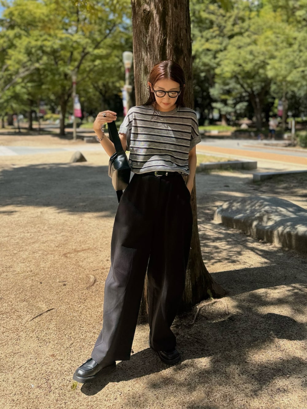 ブラック系のショルダーバッグ、ブラック系のチノパンツ、ブラック系のローファーを着用したレディースの秋コーディネートの4枚目の写真