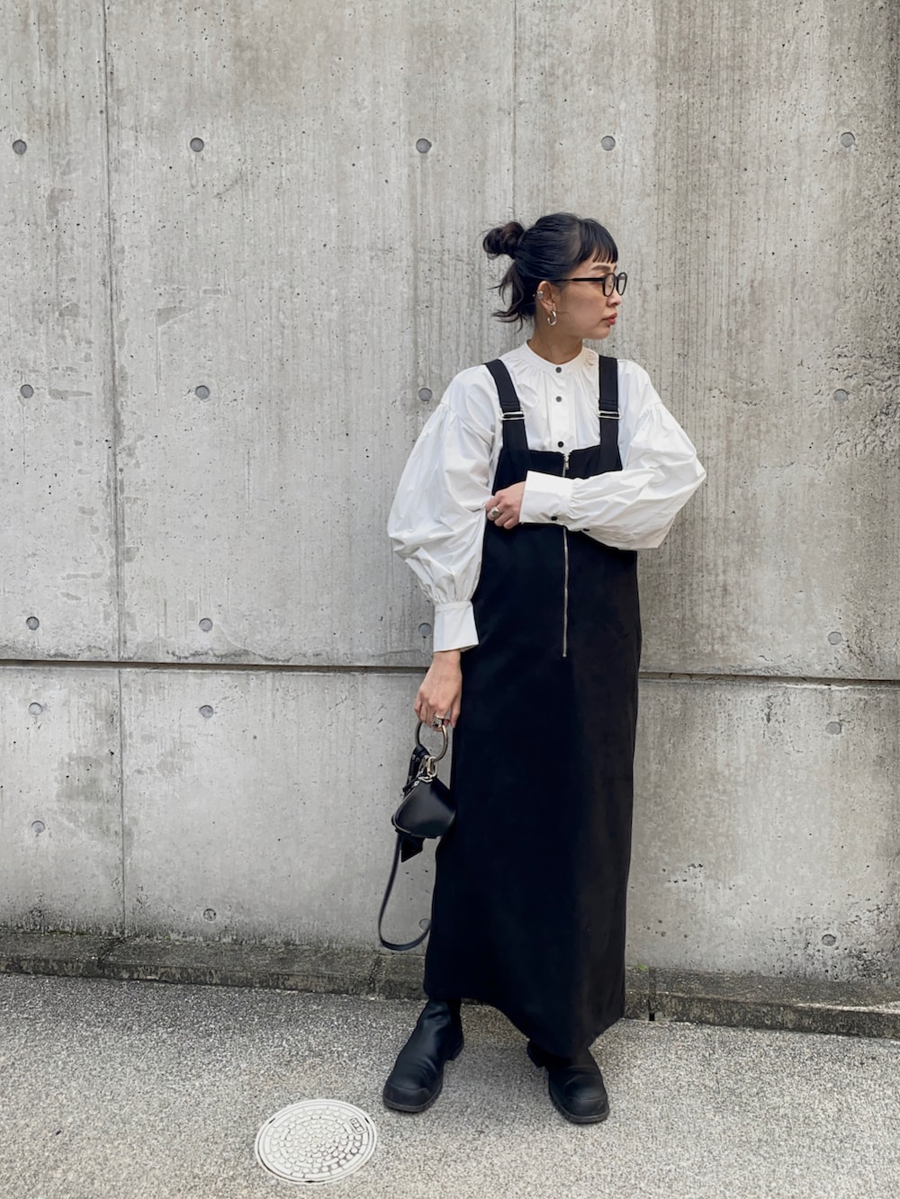 ブラック系のジャンパースカート、ブラック系のショルダーバッグ、ホワイト系のシャツ/ブラウスを着用したレディースの冬コーディネートの3枚目の写真