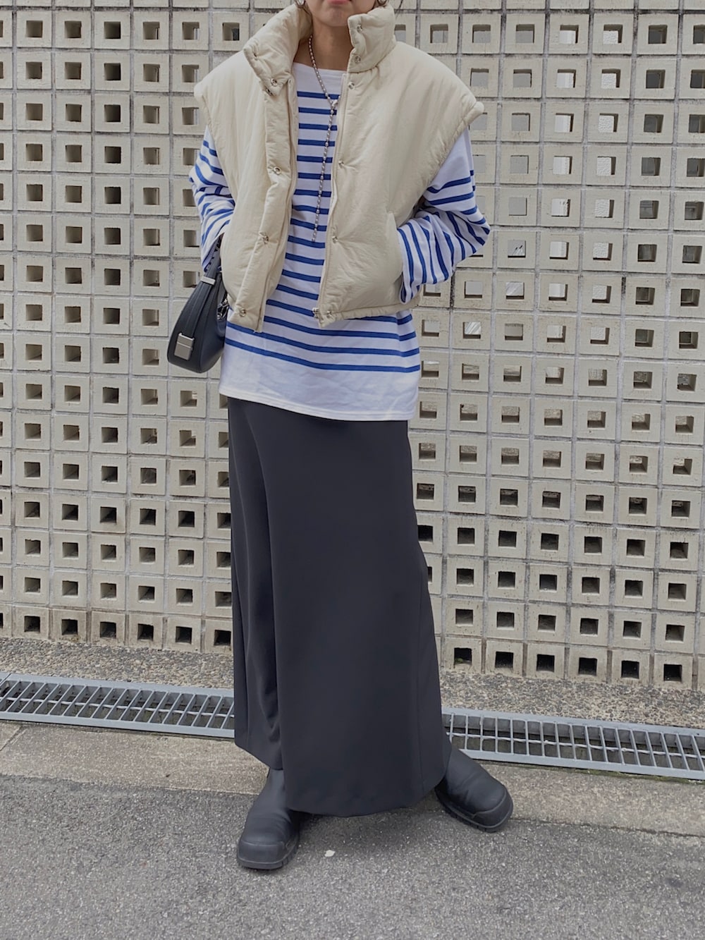 ホワイト系のTシャツ/カットソー、ブラック系のスカート、ブラック系のハンドバッグを着用したレディースの秋コーディネートの2枚目の写真