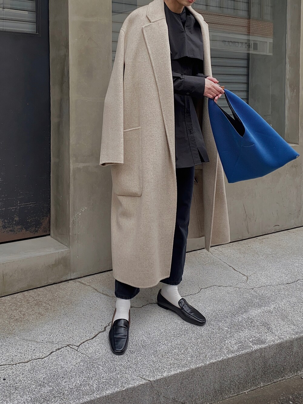 ブラック系のシャツ/ブラウス、ブルー系のハンドバッグ、ホワイト系のチェスターコートを着用したレディースの冬コーディネートの3枚目の写真