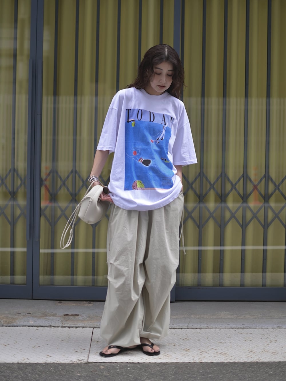 ホワイト系のTシャツ/カットソー、ホワイト系のショルダーバッグ、グレー系のパンツを着用したレディースの夏コーディネートの3枚目の写真