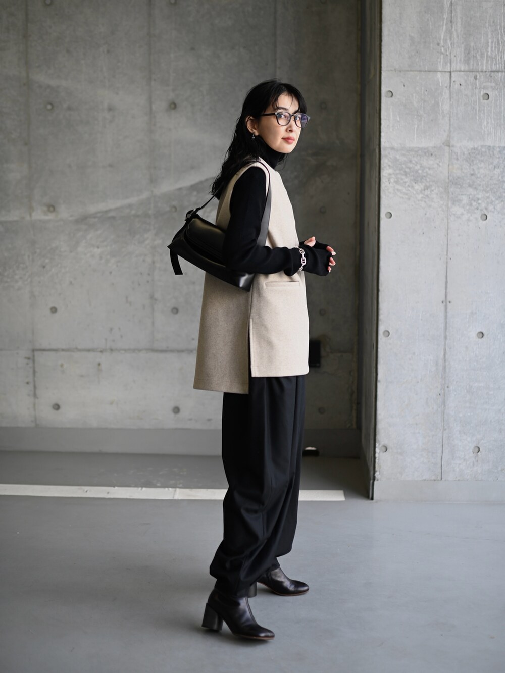 ベージュ系のベスト、ブラック系のスラックス、ブラック系のブーツを着用したレディースの冬コーディネートの2枚目の写真