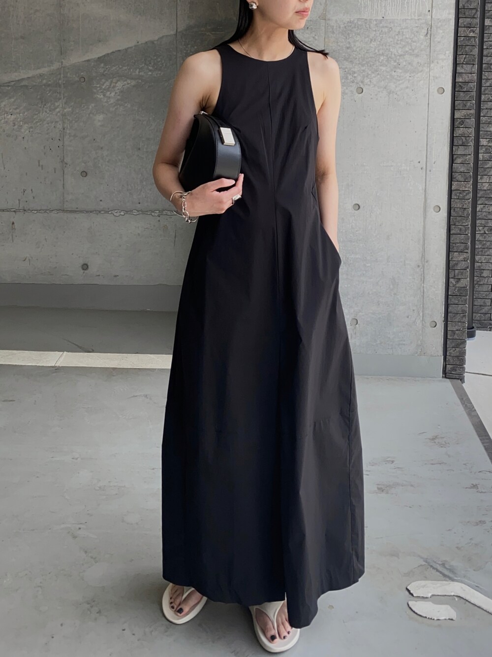 ブラック系のワンピース、ブラック系のハンドバッグ、ホワイト系のサンダルを着用したレディースの夏コーディネートの2枚目の写真