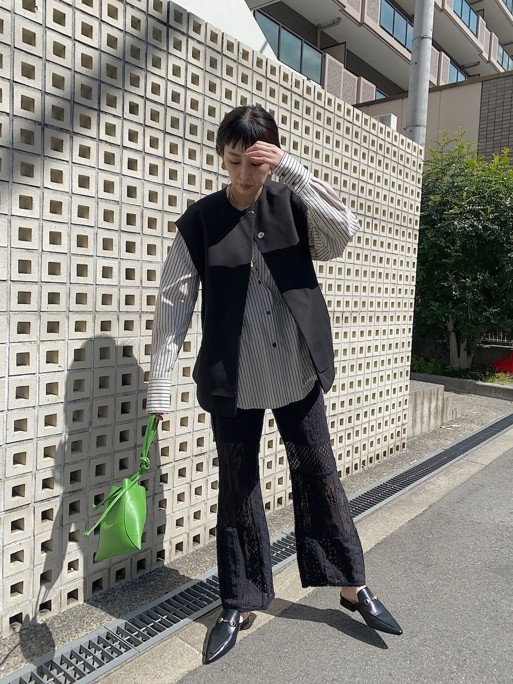 ブラック系のベスト、ベージュ系のシャツ/ブラウス、グリーン系のハンドバッグを着用したレディースの春コーディネートの2枚目の写真