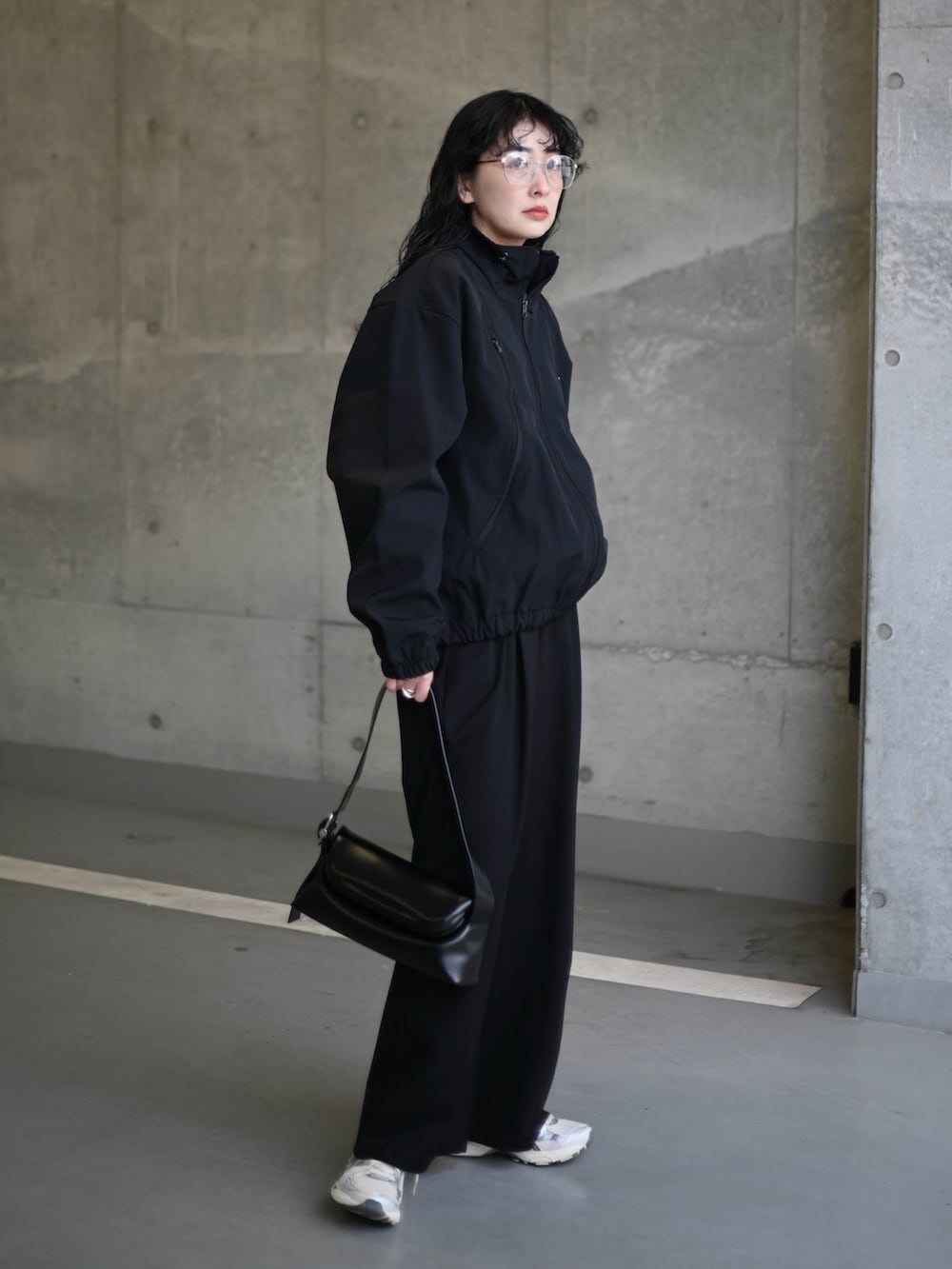 ブラック系のナイロンジャケット、シルバー系のスニーカー、ブラック系のショルダーバッグを着用したレディースの春コーディネートの3枚目の写真
