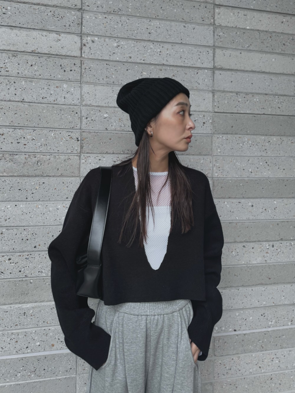 ブラック系のニット/セーター、グレー系のスウェットパンツ、ブラック系のショルダーバッグを着用したレディースの秋コーディネートの3枚目の写真