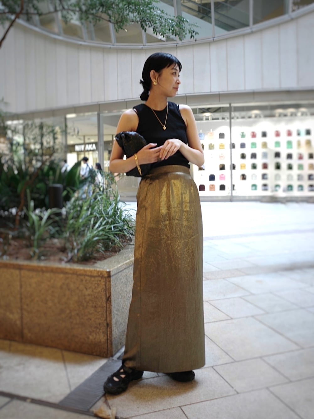 ブラック系のタンクトップ、ゴールド系のスカート、ゴールド系のネックレスを着用したレディースの夏コーディネートの3枚目の写真
