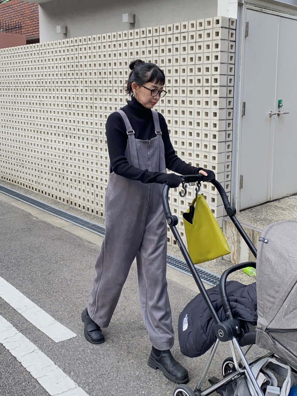 グレー系のサロペット/オーバーオール、イエロー系のハンドバッグ、ブラック系のニット/セーターを着用したレディースの冬コーディネートの2枚目の写真