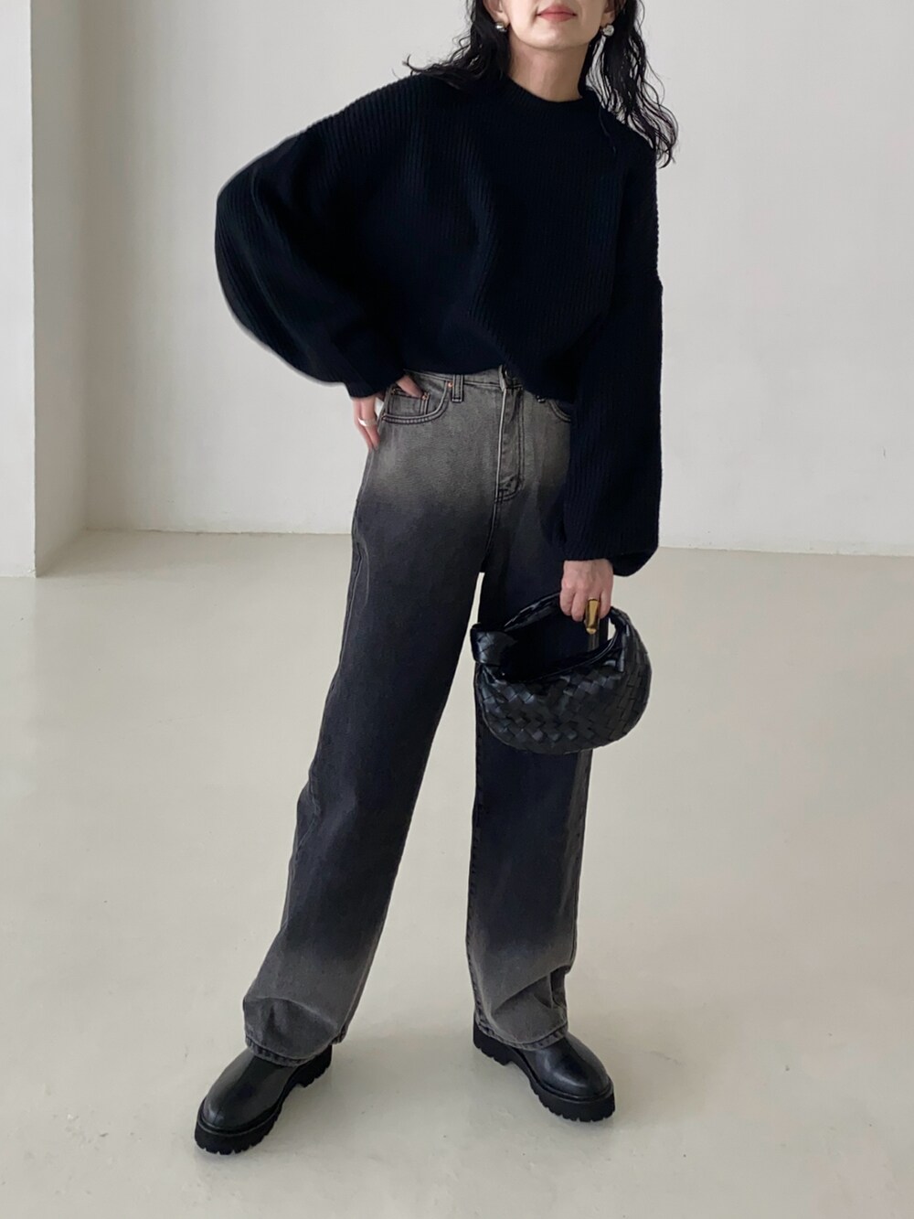 ブラック系のニット/セーター、ブラック系のデニムパンツ、ブラック系のブーツを着用したレディースの春コーディネートの2枚目の写真